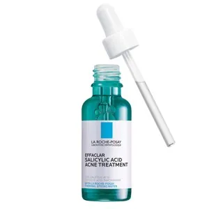 Amber glass vials of acne fighting face serum ingredients on a wooden surface.